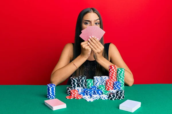 Young Hispanic Woman Playing Gambling Poker Covering Face Cards Skeptic — Stock Photo, Image