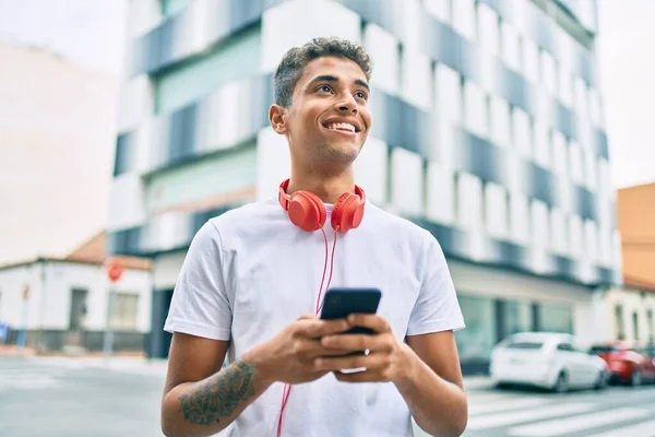 Νεαρός Λατίνος Άνθρωπος Χαμογελώντας Χαρούμενος Χρησιμοποιώντας Smartphone Και Ακουστικά Στην — Φωτογραφία Αρχείου