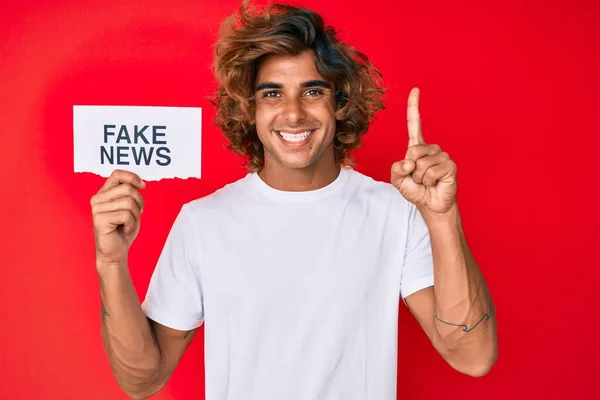 Young Hispanic Man Holding Fake News Banner Surprised Idea Question — Stok fotoğraf