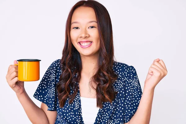 年轻美丽的中国女孩举着咖啡高喊着自豪 高举双臂庆祝胜利和成功 — 图库照片