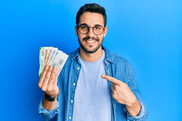 Joven Hispano Sosteniendo Billetes Rublo Rusos Sonriendo Feliz Señalando Con —  Fotos de Stock