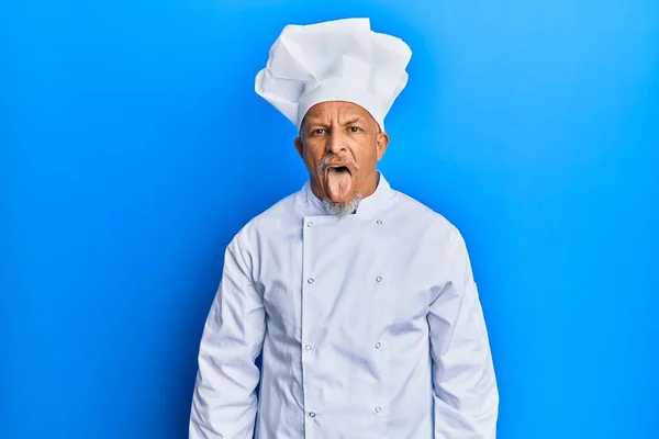 プロのコック制服を着た中年の白髪の男と面白い表情で幸せ舌を突き出す帽子 感情の概念 — ストック写真