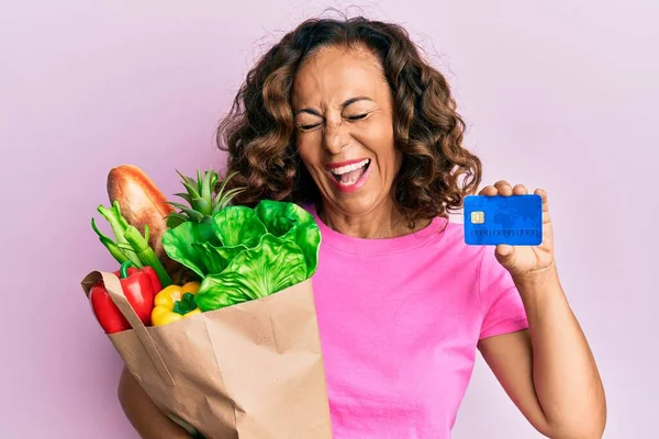 Mujer Hispana Mediana Edad Sosteniendo Comestibles Tarjeta Crédito Sonriendo Riendo — Foto de Stock