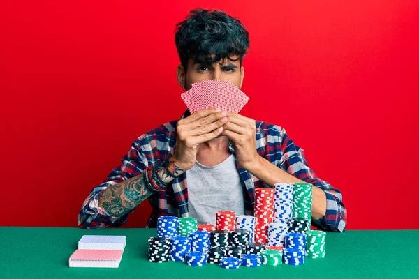 Jovem Hispânico Jogando Poker Cobrindo Rosto Com Cartões Céticos Nervosos — Fotografia de Stock