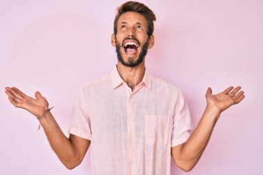 Sakallı, sıradan pembe tişörtlü yakışıklı beyaz bir adam. Deli gibi bağırıyor, agresif bir ifadeyle bağırıyor ve kollarını kaldırıyor. hüsran kavramı. 