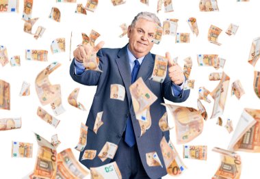 Kıdemli gri saçlı, iş ceketi giyen, elinde olumlu bir jest yapmayı onaylayan, gülümseyen ve başarı için mutlu bir adam. kazanan jest.