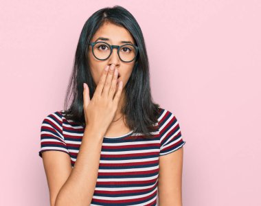 Gündelik kıyafetler ve gözlük takan güzel Asyalı genç bir kadın ağzıyla ağzını kapatmaktan sıkılmış. Huzursuz ve uykulu.. 