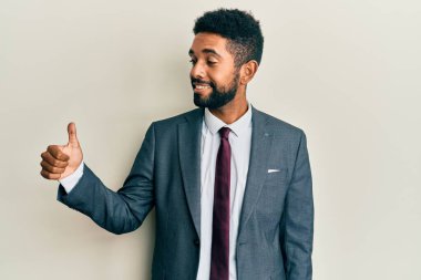 Yakışıklı, sakallı, takım elbiseli, kravatlı, gururlu, gülümseyen, baş parmak kaldıran bir adam. 