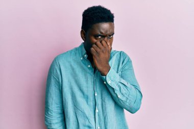 Yakışıklı, sıradan kıyafetler giyen, pis ve iğrenç bir koku alan, nefesini burnunda tutan siyah bir adam. Kötü kokuyor. 