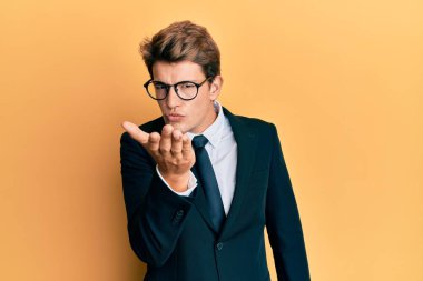 Yakışıklı, beyaz takım elbiseli ve kravatlı bir adam kameraya bakıp havada öpücükler savuruyor. Güzel ve seksi. aşk ifadesi. 