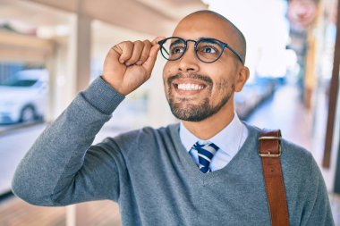 Genç Afrikalı Amerikalı iş adamı gülümseyerek şehirde mutlu bir şekilde yürüyor..