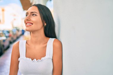 Genç Latin kız gülümsüyor. Mutlu mesut şehrin duvarına yaslanıyor..