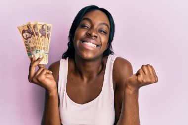 Genç Afrikalı Amerikalı kadın elinde Macar forint banknotlarıyla gururla bağırıyor zaferi ve başarıyı kutluyor. 