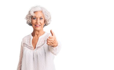 Kıdemli, gri saçlı, sıradan kıyafetler giyen, dostça gülümseyen, selamlaşmak için el sıkışan bir kadın. başarılı iş. 