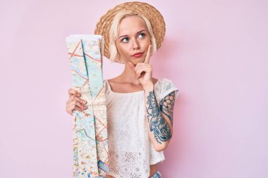 Sarışın, yaz şapkası takan genç bir kadın elinde şehir haritası olan ciddi bir yüzle eli çenesinde soru soran, kafa karıştırıcı bir fikir hakkında düşünceli bir kadın. 