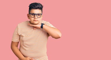 Sıradan kıyafetler ve gözlük takan küçük bir çocuk bıçakla boğazı kesiyor, saldırganlığı şiddetle tehdit ediyor. 