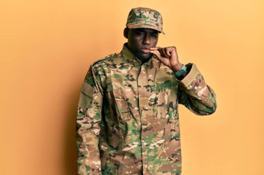 Asker üniforması giyen, ağzı ve dudakları parmaklarıyla kapanmış genç Afro-Amerikan bir adam. gizli ve sessiz, tabu konuşması 