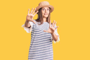 Yazlık şapkalı, korku ifadesi yüzünden dehşete düşmüş beyaz bir kadın. El kol hareketi yapmayı kes, şok içinde bağır. panik konsepti. 