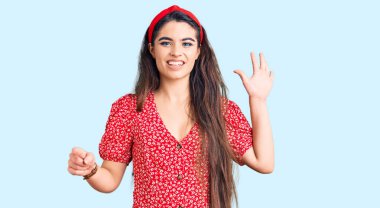 Yazlık elbise giyen esmer genç kız gülümseyerek kendinden emin ve mutlu gülümserken beş numarayı işaret ediyor.. 