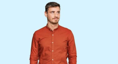 Yakışıklı, beyaz bir adam, günlük kıyafetler giyiyor, gülümsüyor, yan tarafa bakıyor ve düşünüyor.. 