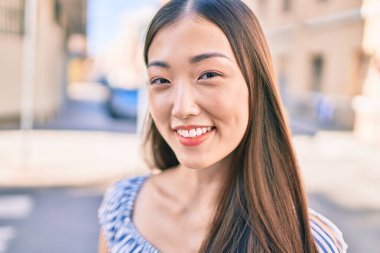 Genç Çinli kadın gülümsüyor. Şehrin caddesinde mutlu bir şekilde yürüyor..