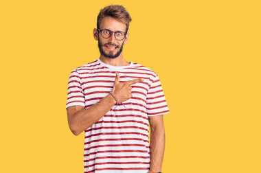 Sakallı, sıradan giyinmiş, gözlüklü yakışıklı, endişeli, endişeli ve şaşırmış bir ifade takınıyor. 