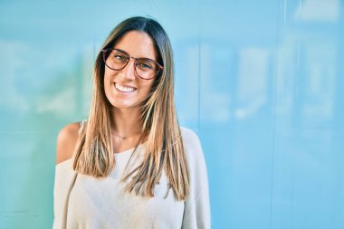 Genç beyaz kadın gülümseyerek şehirde mutlu mesut yürüyor..