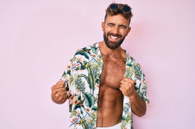 Gündelik yaz kıyafetleri giyen genç İspanyol adam pozitif ve mutlu görünüyor ve kendine güvenen bir gülümsemeyle dişlerini gösteriyor. 