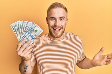 Elleri havada genç, beyaz bir adam başarıyı mutlu bir gülümsemeyle ve kazanan bir ifadeyle kutluyor. 