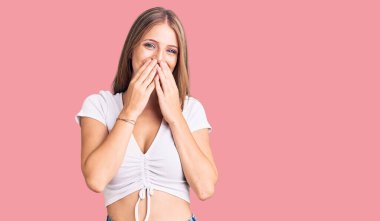 Genç, güzel, sarışın bir kadın, günlük beyaz tişört giyiyor, gülüyor ve utanıyor kıkırdıyor. Ağzı ellerle, dedikoduyla ve skandal konseptiyle örtüyor. 