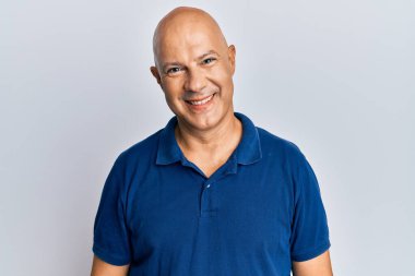 Orta yaşlı kel bir adam mutlu ve havalı bir gülüşü olan sıradan kıyafetler giyiyor. şanslı kişi. 