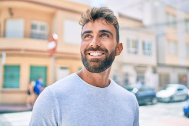 Genç İspanyol adam gülümseyerek şehirde mutlu bir şekilde yürüyor.