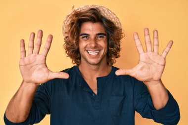 İspanyol şapkalı genç adam 10 numarayı gösterip işaret ederken kendinden emin ve mutlu gülümsüyor.. 