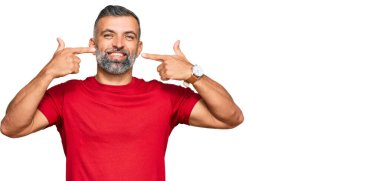 Orta yaşlı, sıradan kıyafetler giyen, neşeli gülümseyen, parmaklarıyla ve ağzıyla işaret eden yakışıklı bir adam. diş sağlığı kavramı. 