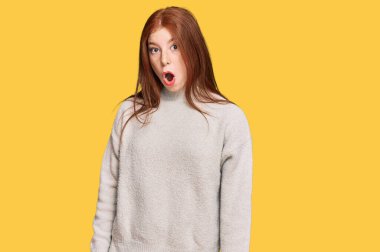 Young read head woman wearing casual winter sweater scared and amazed with open mouth for surprise, disbelief face 