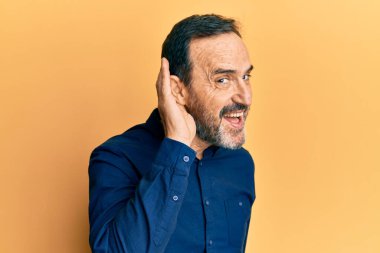 Orta yaşlı İspanyol bir adam gündelik kıyafetler giyip sırıtarak kulaktan kulağa dedikodu ve dedikoduları dinliyor. Sağırlık kavramı. 