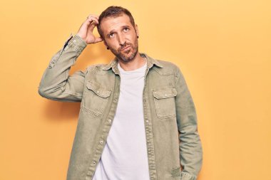 Gündelik kıyafetler giyen genç yakışıklı adam kafaları karıştırır ve soru sorar. Şüpheyle kararsız, kafa kafaya düşünerek. Düşünceli kavram. 