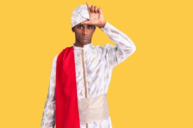 Afrikalı yakışıklı adam geleneksel Sherwani sari kıyafetleri giyiyor. Alnında parmakları olan insanlarla dalga geçiyor. Ezik hareketler yapıyor, alay ediyor ve hakaret ediyor.. 