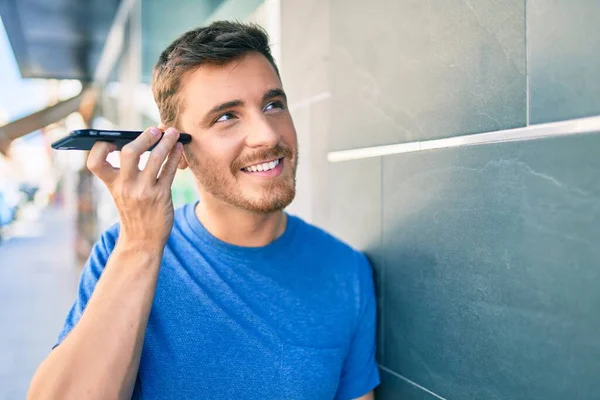 Young Caucasian Man Smiling Happy Listening Audio Message Using Smartphone — Stock Photo, Image