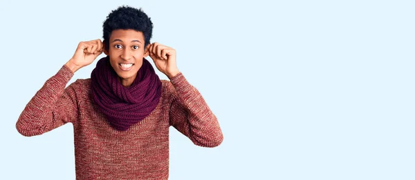 年轻的非洲裔美国男人穿着休闲的冬季毛衣和围巾 微笑着用手指拉耳朵 滑稽的手势 试镜问题 — 图库照片