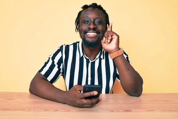 Jovem Afro Americano Com Tranças Usando Smartphone Sentado Mesa Surpreso — Fotografia de Stock