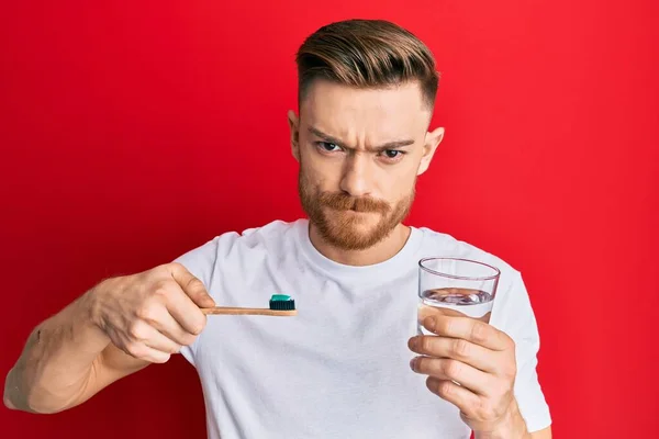 Young Redhead Man Holding Toothbrush Toothpaste Glass Water Skeptic Nervous — Stock Photo, Image