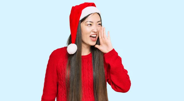 若い中国人女性のクリスマスの帽子を叫び 大声で口の上に手で横に叫んで身に着けている コミュニケーションの概念 — ストック写真