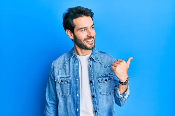 Jovem Hispânico Vestindo Roupas Casuais Apontando Polegar Para Lado Sorrindo — Fotografia de Stock