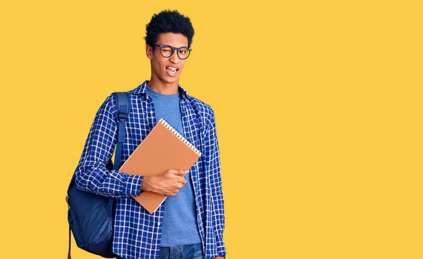 Jovem Afro Americano Vestindo Mochila Estudantil Segurando Livro Piscando Olhando — Fotografia de Stock