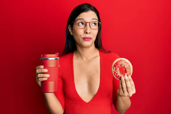 Молодая Латинская Женщина Ест Пончики Пьет Кофе Улыбаясь Глядя Сторону — стоковое фото