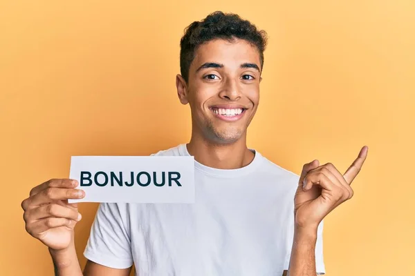 Joven Hombre Afroamericano Guapo Sosteniendo Bonjour Palabra Saludo Francés Sonriendo —  Fotos de Stock