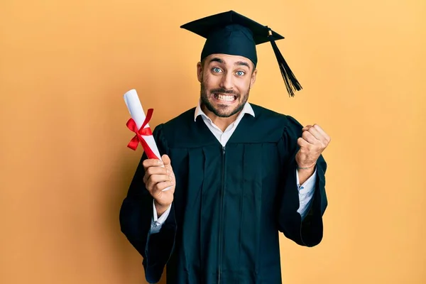 Joven Hispano Vestido Con Bata Graduación Sosteniendo Diploma Gritando Orgulloso — Foto de Stock