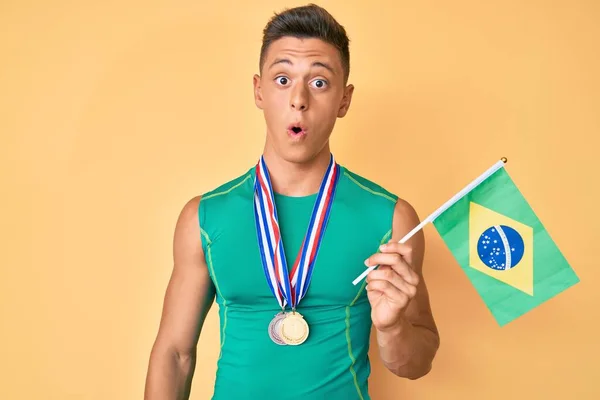 Молодой Латиноамериканец Спортивной Одежде Медалях Бразильским Флагом Испуганный Удивленный Открытым — стоковое фото