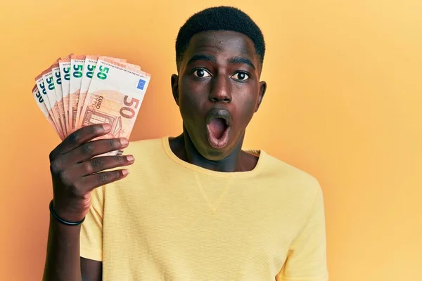 Νεαρός Αφροαμερικάνος Που Κρατάει Χαρτονομίσματα Ευρώ Φοβισμένος Και Έκπληκτος Ανοιχτό — Φωτογραφία Αρχείου